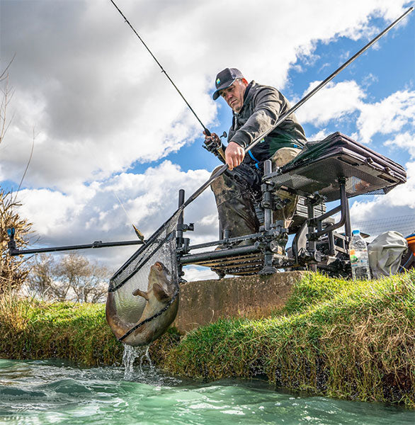man catching fish with fishing rod and net